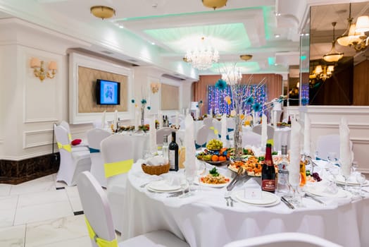 covered dining table in bright white luxury Banquet hall for wedding events
