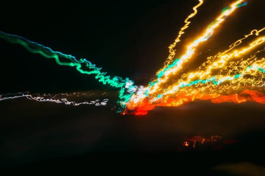 dark background with blurred traces from the lights of cars on the road through the glass at speed