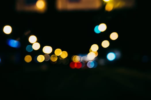 blurred city lights and lanterns in the shape of bokeh through the glass of the car on the road