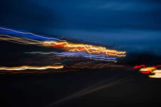 abstract blurred colored marks from fast-moving cars on night road