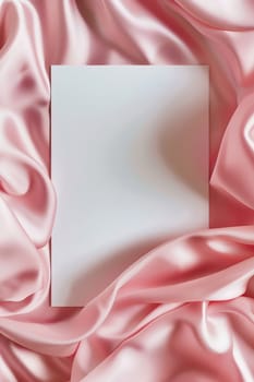 Minimalist aesthetic mockup of white blank A5 envelope on pink silk fabric.