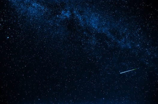 shooting star in background a starry blue dark sky at night