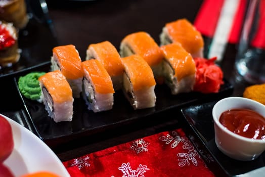 rolls with fish and avocado on a plate with sauce, ginger and wasabi