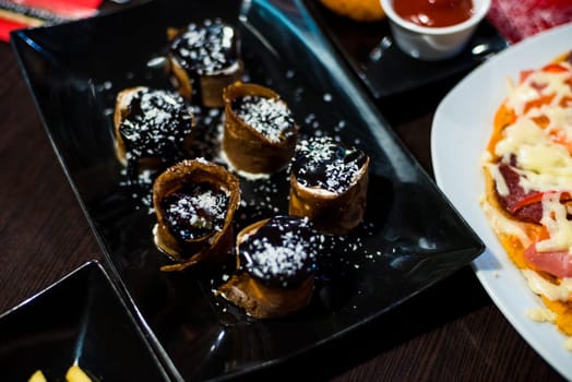 sweet rolls with topping for a delicious dessert on black plate