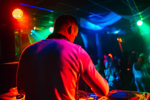 DJ in a nightclub mixes music for a party