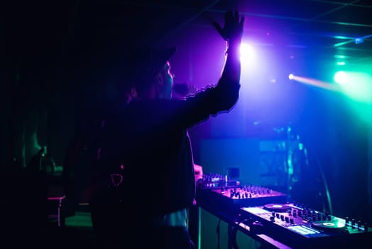 MC DJ waving his hands and shouting into the microphone in a nightclub at the party blurred and in motion