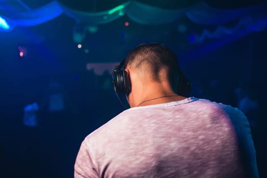 head of a DJ with headphones playing at the event in a nightclub