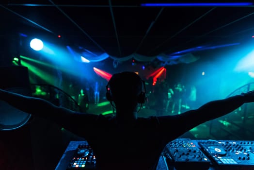silhouette of the DJ waving his hands in different directions at a merry party in the night club music event