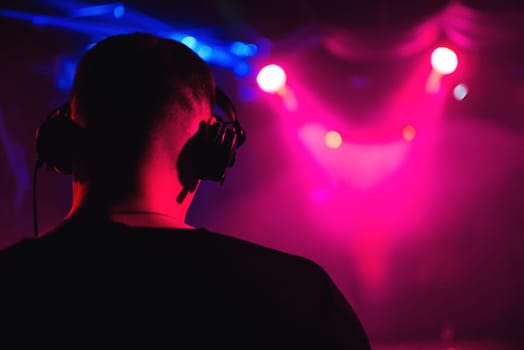 head DJ headphones from the back closeup of a musical event with bright blurred background