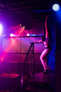 young slim girl dancer dancing in a nightclub on stage with long dark hair