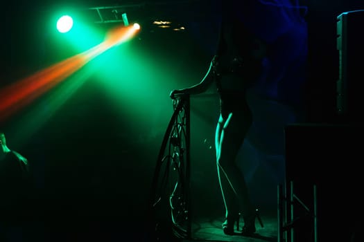 dancer silhouette with shapely long legs in a nightclub on stage