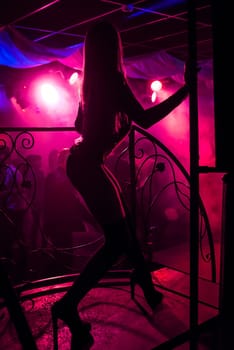 young girl go-go with a slender sexy figure posing with long legs in high heels on stage