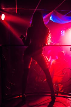 blurred silhouette of a young sexy slim girls go-go at the club