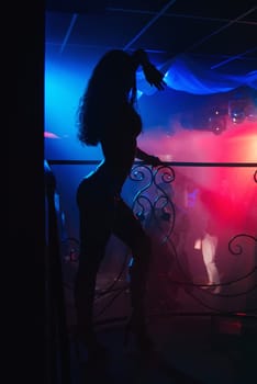 silhouette of a slender thin sexy dancers, go-go on the night club stage