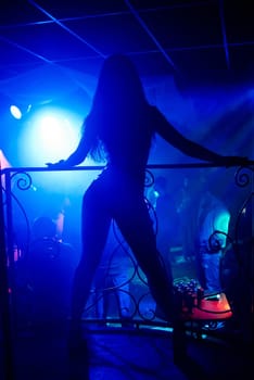silhouette of a slender thin sexy dancers, go-go on the nightclub scene with long hair and a good figure