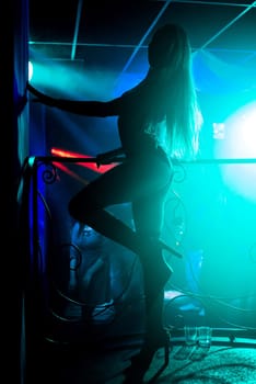 young girl with a slender body dancing on the stage dance floor night club with bright colored background