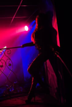 girl posing at a wall in a nightclub on stage silhouette with red backlight