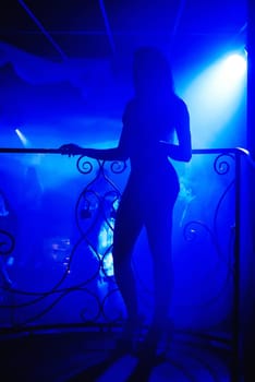 silhouette of a girl posing on the stage of a nightclub with a young sexy body