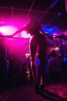 slender young girl dancer with hot body and long legs and a beautiful bend on the long heels in a night club