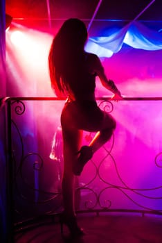 young girl with slender body dancing on stage dance floor night club with colored background