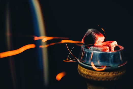 coals on the bowl of the hookah for tobacco Smoking close up with sparks on a dark background