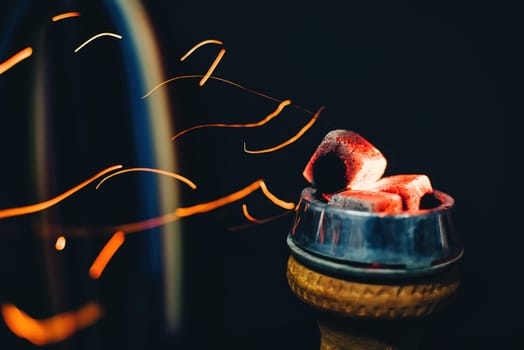 bowl of hookah with hot coals and red sparks flying for tobacco and Smoking and a traditional Asian holiday closeup