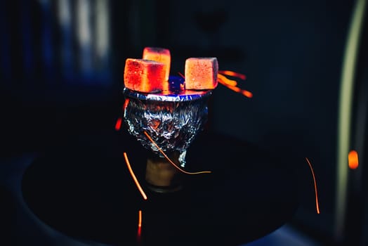 hot coals on the foil on the bowl of the hookah tobacco Smoking on dark background
