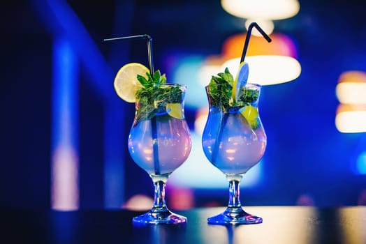 two glass of Mojito cocktail with straws lime and mint at the party on bright blurred background