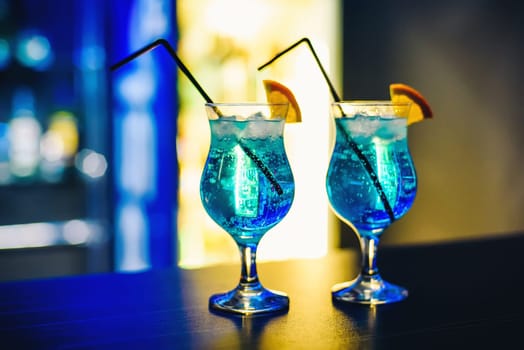 martinis in glasses with ice on the bar with orange and blurred background