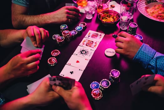 game of poker cards and chips on the table with the hands of the players view from above