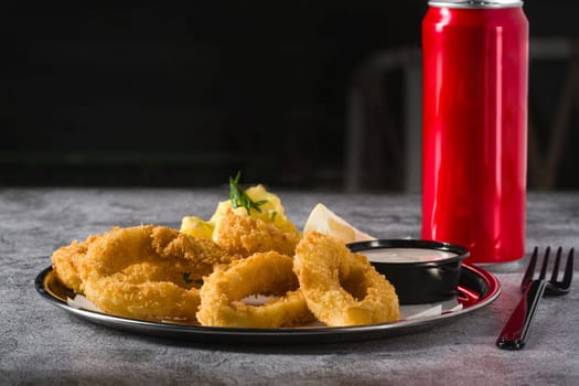 Fried calamari with potato salad next to it on stone table