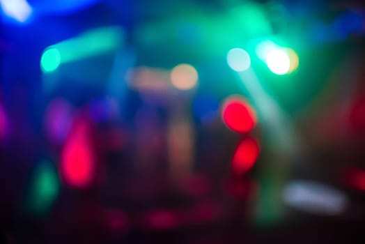 blurred abstract background of colored lights in a night club with bokeh out of focus and bright spots