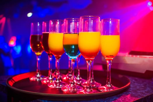 glasses with cocktails for a party in a night club colored with a bright color background