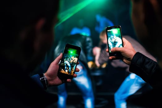 men shoot videos on smartphones at an entertainment event