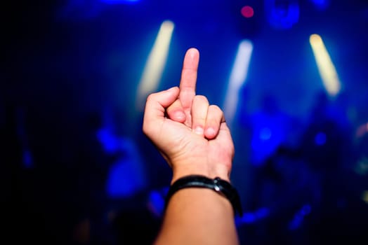 gesture of aggression and negativity fuck you shows a male hand closeup with blurred colored background