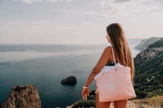 Woman travel sea. Happy tourist taking picture outdoors for memories. Woman traveler looks at the edge of the cliff on the sea bay of mountains, sharing travel adventure journey.