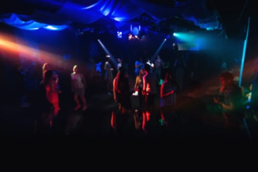 blurred people dancing on the dance floor in a nightclub on the dance floor with colorful background