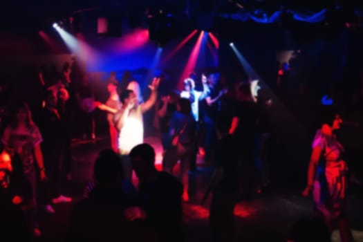 blurred people dancing on the dance floor at a night club concert party