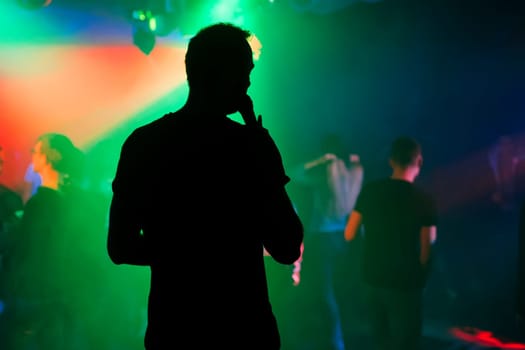 silhouette of the presenter with a microphone on the stage of a nightclub at a concert