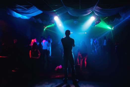 silhouette of the presenter on stage at a concert in a nightclub with a dark colored background