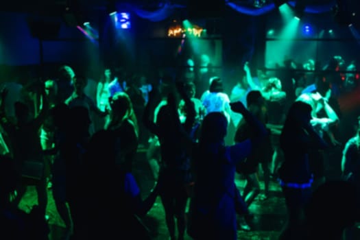 blurred silhouettes dancing merry men on the dance floor at the concert in a nightclub