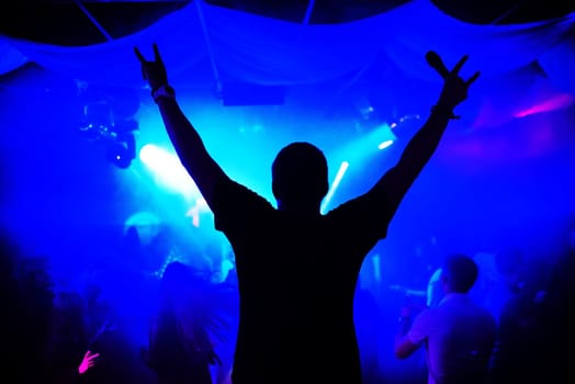 silhouette of a man leading with a microphone on a concert night club with blue smoke and the lights