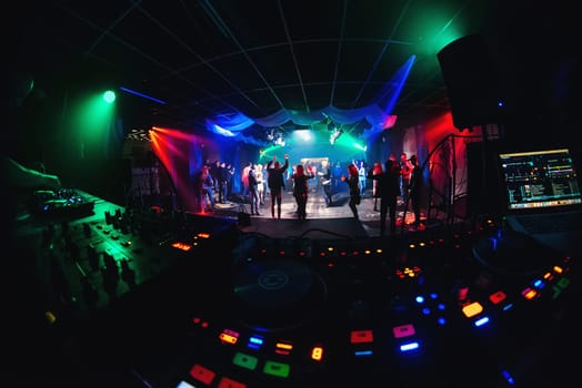 night club with dancing people on the dance floor and stage for musical event and mixer the DJ and his booth