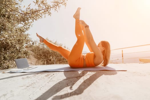 Fitness woman sea. Outdoor workout on yoga mat in park near to ocean beach. Female fitness pilates yoga routine concept. Healthy lifestyle. Happy fit woman exercising with rubber band in park.