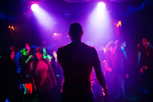 blurred silhouette of the MC with a microphone on stage of nightclub