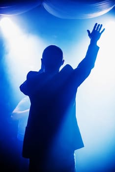 blurred silhouette of the MC with a microphone on stage of nightclub