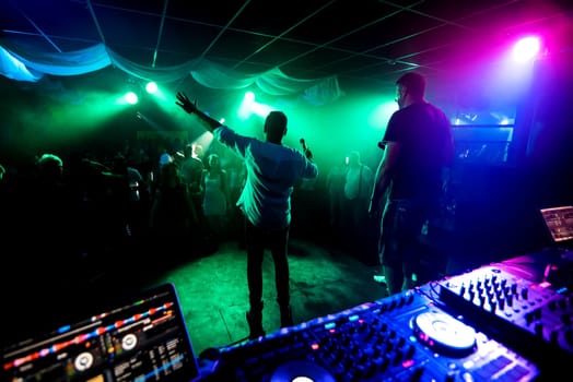 silhouettes of men leading musicians on the dance floor at the night club concert
