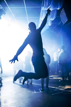 blurred silhouette of the MC with a microphone on stage of nightclub