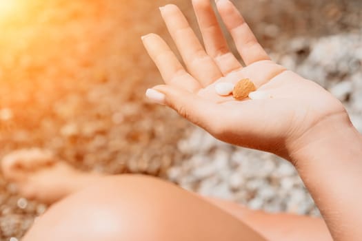 Woman eating milky almond nuts. A young caucasian woman choping fresh green almond after morning fitness yoga near sea. Only hands are visibly. Healthy vegan food. Slow motion. Close up