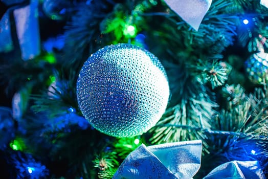 ball on the Christmas artificial trees branches on branches closeup with colorful lights and the blurred background